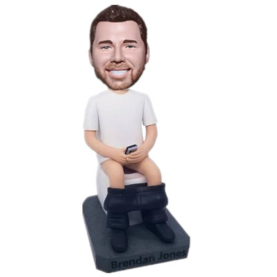 Joking Bobblehead Man Sitting on The Toilet with Phone in Hands